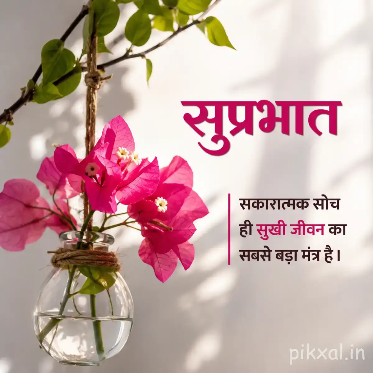 Pink flowers arranged in a small glass vase against a softly lit white background with a Hindi Good Morning wish